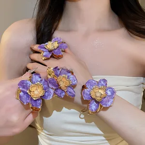 Vista macro dettagliata del braccialetto e dell'anello a fiore viola e oro su una modella.