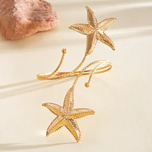 Detailopname van gouden zeester armring met getextureerde details en open ontwerp