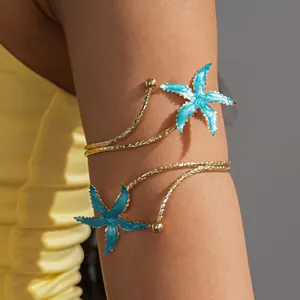 Detailweergave van een gouden armmanchet met twee turquoise emaille zeesterren op een bovenarm