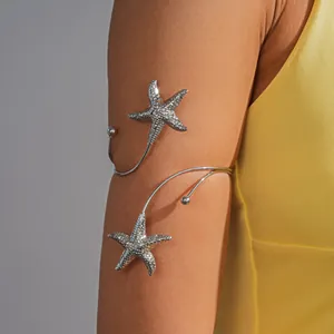 Detail van een zilveren zeester armring gedragen bij een zonnige gele vakantiejurk.