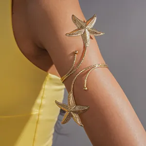 Detail van een gouden zeester armring gedragen op de arm voor een vakantiestijl