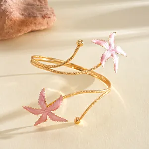Gedetailleerde opname van een gouden armmanchet met roze geëmailleerde zeesterren