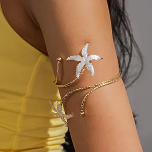Gedetailleerde weergave van een gouden zeester armring op de bovenarm van een model.