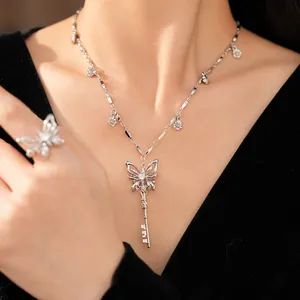 Detailed view of elegant zircon butterfly key necklace and matching ring on model