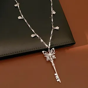 Detailed view of silver butterfly key necklace with flower charms and zircon stone.