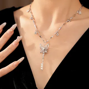 Detailed shot of silver butterfly key necklace with zircon floral accents on model.