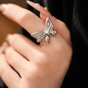 Close-up of a silver butterfly ring with a sparkling zircon on a woman's finger.