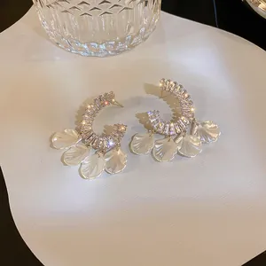 Detail shot of elegant crescent earrings with sparkling stones and white shell petals