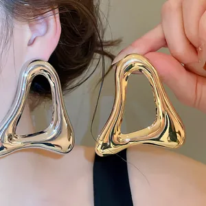 Detailed view of chunky hollow triangle metal earrings in gold and silver finish