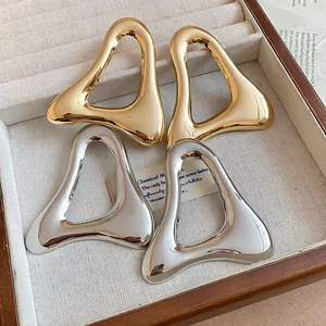 Detailed view of retro hollow triangle metallic earrings in polished gold and silver