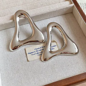 Detailed macro view of oversized hollow triangle metal stud earrings in shiny silver