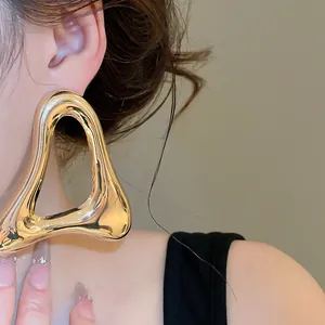 Close-up view of a large vintage hollow triangle metal earring in a polished gold finish