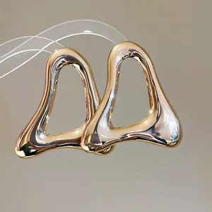 Detail view of oversized gold hollow triangular earrings featuring a molten metal texture