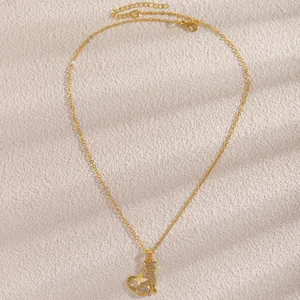 Detailansicht einer goldenen Kette mit Katzen- und Schmetterlingsanhänger und glitzernden Zirkonia.