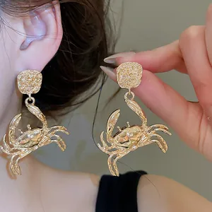 Detail view of golden crab-shaped drop earrings with shimmering rhinestone accents.