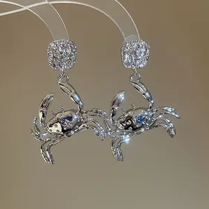 Detailed close-up of shiny silver crab earrings with sparkling stones and textured details.