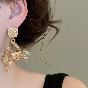 Detailed shot of golden crab statement earrings featuring unique hammered texture
