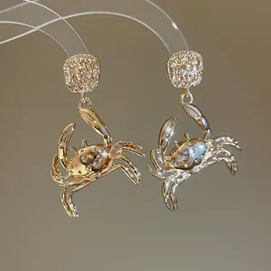 Detailed macro view of gold-toned crab earrings with hammered texture and ocean-style design