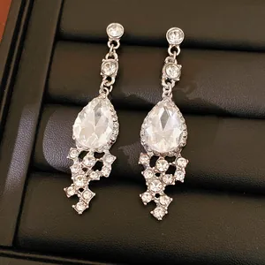 Detailed macro shot of silver teardrop earrings with clear sparkling crystals and rhinestones
