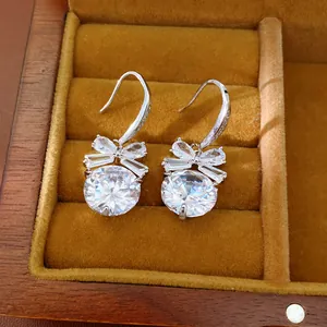 Détail des boucles d'oreilles nœud argentées avec de gros zircons ronds brillants