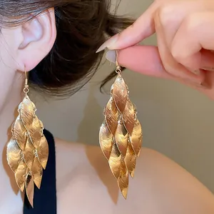 Detailed close-up showing elegant gold metal leaf tassel earrings on a model's ear