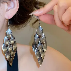 Detailed view of retro metallic leaf tassel drop earrings with a brushed silver finish.
