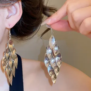 Close-up of elegant silver metallic multi-layered leaf tassel drop earrings on ear