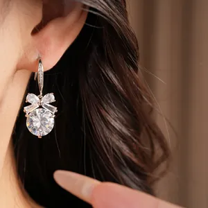 Détail en gros plan d'élégantes boucles d'oreilles rondes en zircon avec nœud sur modèle