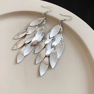 Close-up of elegant silver metal leaf tassel earrings showing textured leaf hook design.