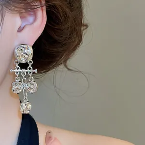 Detail shot of vintage silver-tone wrinkled metal tassel earrings on model's ear.