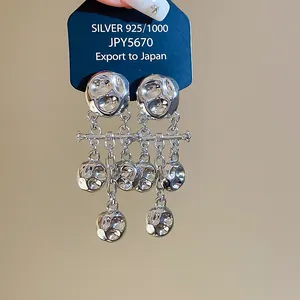 Close-up of silver-toned crumpled metal drop earrings with long tassels on display card