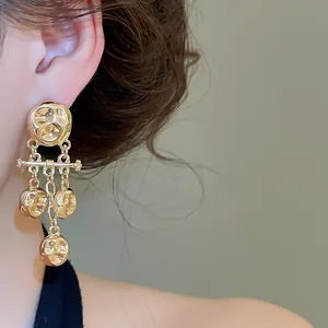 Detailed macro shot of vintage gold-tone wrinkled metal tassel drop earrings.