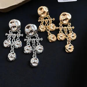 Detailed view of gold and silver crinkled metal tassel earrings on black fabric.