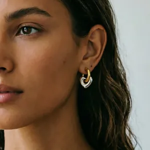 Two-tone detachable heart hoop earrings in gold and silver finish on model ear.