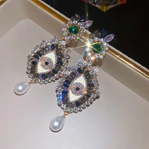 Elegant vintage rhinestone eye stud earrings with white pearl pendants in a gold finish
