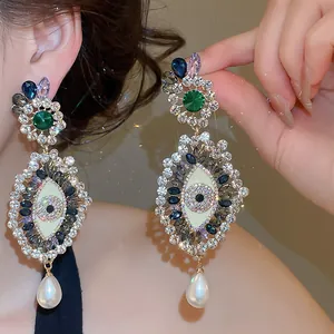 Detail view of luxury vintage eye earrings with colorful rhinestones and pearl drop