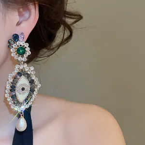 Detailed shot of vintage evil eye dangling earrings with sparkling crystals and a pearl.