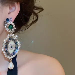 Detailed close-up view of vintage crystal eye earrings featuring a white pearl drop