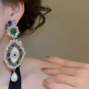 Close-up detail of ornate French vintage earrings with crystal evil eye and pearl drop