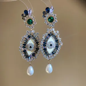 Close-up of ornate evil eye earrings with colorful crystals and pearl drops