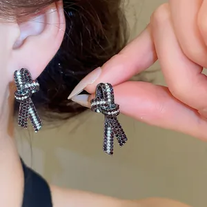 Primo piano dettagliato di eleganti orecchini a fiocco con cristalli sull'orecchio.