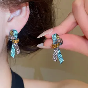 Dettaglio di vivaci orecchini a perno a nodo con strass multicolore sull'orecchio