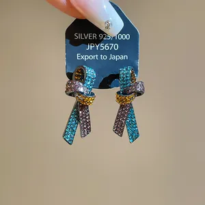 Primo piano di orecchini a forma di nodo con strass multicolori su un cartoncino