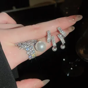 Close-up of elegant silver-tone jewelry set featuring a sparkling pearl ring and earrings.