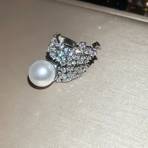 Macro view of a luxurious sparkling zirconia and pearl ring on a textured gold surface