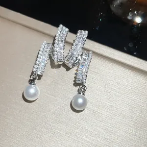 Close-up view of elegant zircon and pearl drop earrings with a luxury sparkling finish