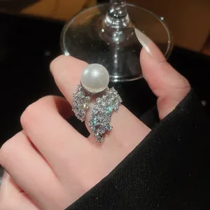 Elegant pearl ring featuring shimmering zircon pavé details on a finger, macro view.