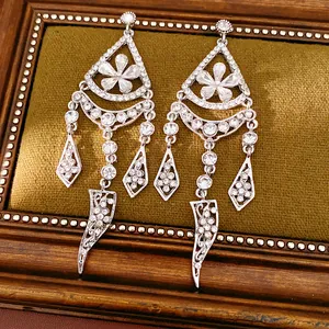 Close-up of elegant silver-toned earrings with flower patterns and crystal tassels