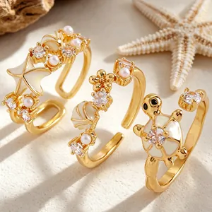 Vista detallada de anillos dorados de tema marino con conchas, estrellas de mar y perlas.