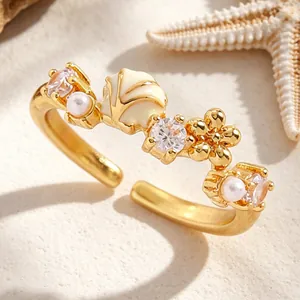 Detalle de un anillo de concha dorada de lujo con perlas y circonitas sobre la arena.
